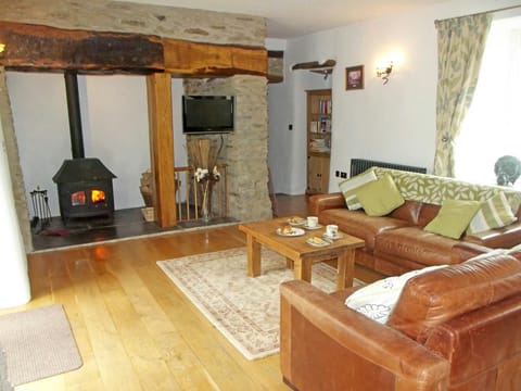 Open plan living room with sofas, coffee table, wood burner and wall mounted TV