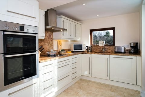 Kitchen at Glandwr with oven, microwave, kettle and kitchen equipment, tiled floor