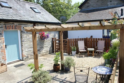 The outside seating area in the garden with flowers and plants in pots