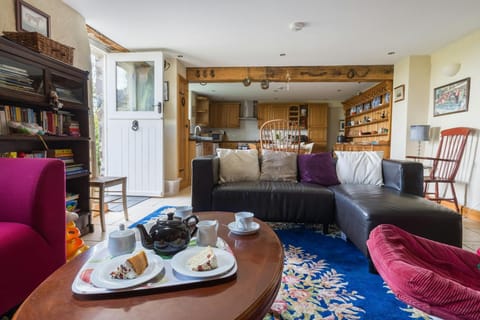 The Stables sitting area with leather sofa, coffee table, red armchairs and book shelves