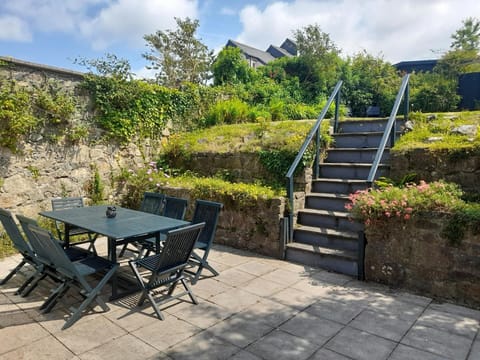 Patio area; table with eight chairs and steps leading to the garden