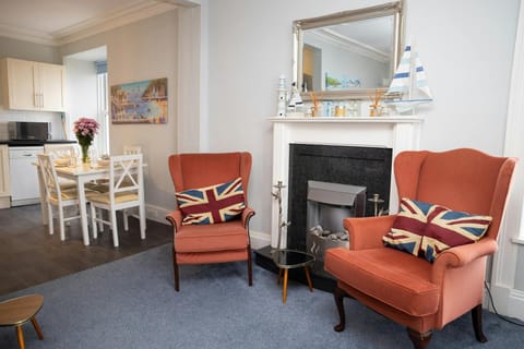 Two armchairs next to an electric fire with a mirror above