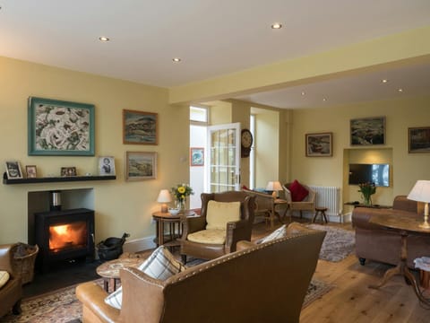 Lounge with wood burner, leather sofas, armchairs, wicker chairs, side tables with lamps and TV