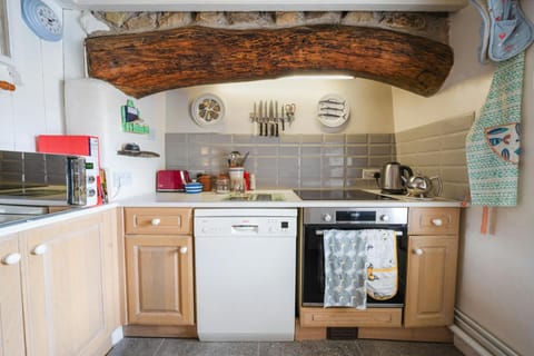 Kitchen with electric cooker and dishwasher with large original beam above