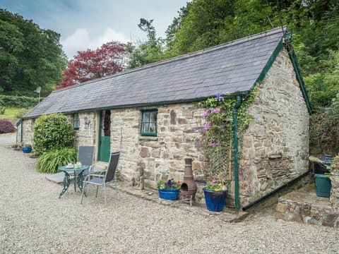 Cottage with gravel patio area with small table and chairs, surrounding trees