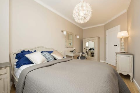 Stylish bedroom with a large bed, chandelier, and elegant wall decor.
