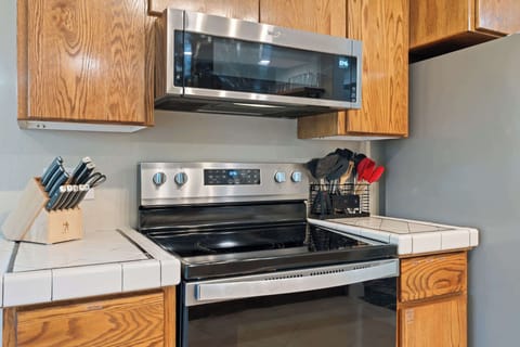 Fully equipped kitchen with stainless steel range, microwave, cookware, and utensils ready for home-cooked meals.