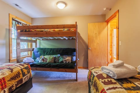 The bedroom includes a rustic bunk bed alongside an additional sleeping area. Wood finishes and mountain cabin décor create a comfortable lodging space in Bryson City.