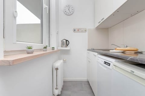 A functional kitchenette with a stove, sink and wide worktop – the interior is well lit.