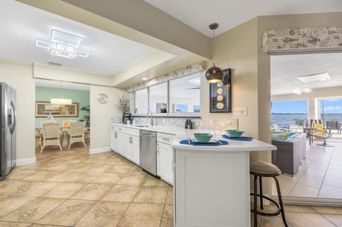 - Open concept kitchen connects easily to indoor dining and outdoor seating
- Eat in bar, full size fridge, and tile floors make hosting a breeze
- Views extend all the way out to the patio and sparkling waterfront beyond