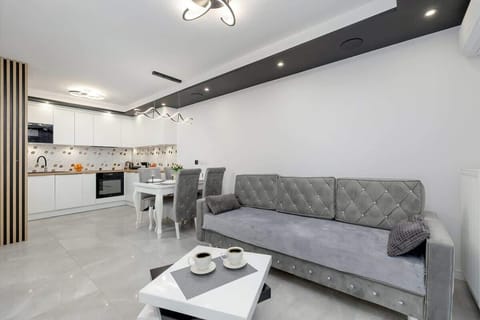 Modern living room with gray sofa, white floors, and recessed ceiling light.