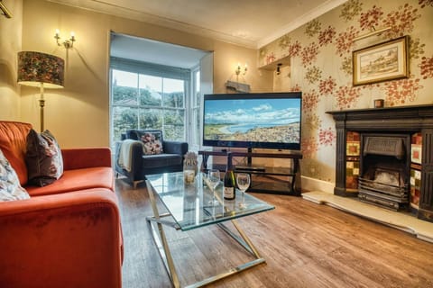 Sofa, armchair, large TV, standard lamp, ornamental fire place, and coffee table