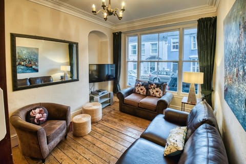 Large window. Wooden floor boards. Two sofas and armchair