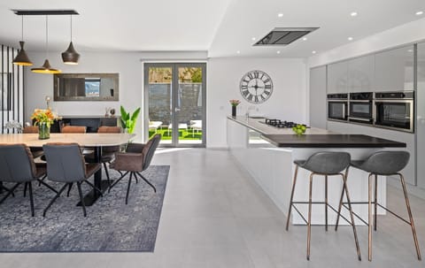 A microwave, coffee maker (Nespresso), wine fridge, toaster, kettle, dining table, and two bar stools