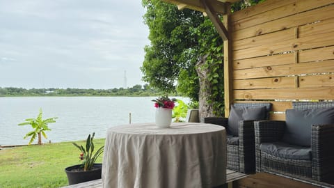 Covered deck with lake views, cozy seating, and peaceful nature vibes.