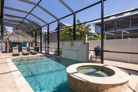 Heated Pool and Spa with cage and tiki hut with large screen TV and string lights