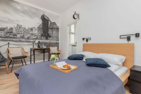 Cozy bedroom with a double bed, mural of Gdańsk Old Town, and wooden elements.