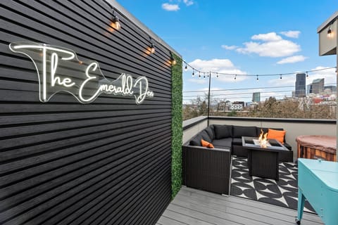 Relax at The Emerald Den's rooftop lounge with string lights and Seattle views!