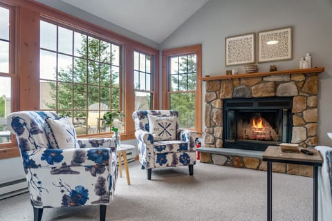 Living Room: Bright windows invite nature in, while a stone fireplace awaits your favorite stories!