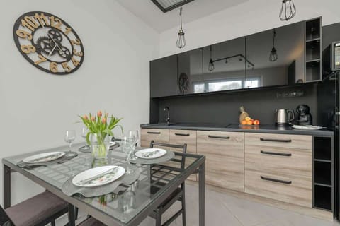 A modern kitchen with wooden cabinets and a black countertop. Includes a coffee maker and essentials for cooking.