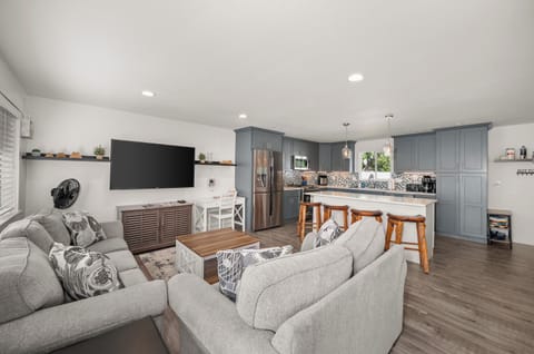 Bright open living space with comfy seating, big TV, and modern kitchen