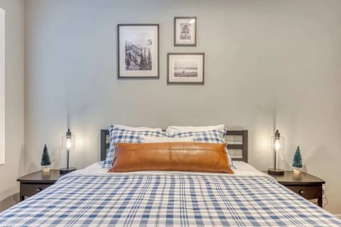 Cozy up in this inviting bedroom with mountain-chic plaid bedding, warm leather accents, and soft lighting—your perfect retreat after a day of adventure.