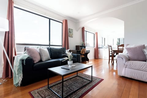 Cozy open-plan living area featuring comfortable seating, a coffee table, and an open view through to the dining area and kitchen.