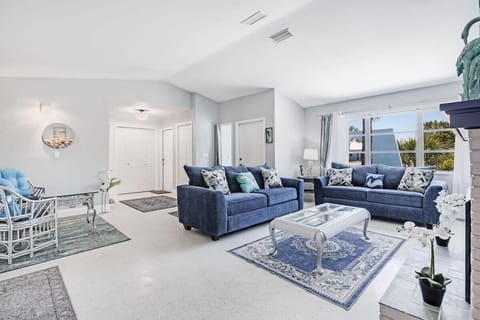 Spacious and light filled living room with multiple sofas, vaulted ceilings, and a large flat screen TV