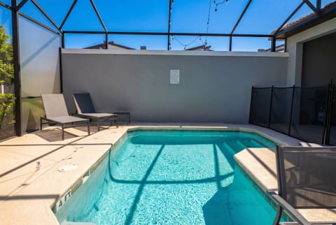 Step outside to your private pool area, where sun-kissed tiles and sleek gray loungers await. The pool's crystal-clear water invites you to relax under the overhead string lights, perfect for evening enjoyment.