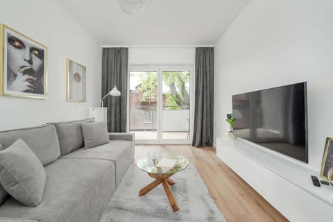 A cozy living room space with a sofa, coffee table, and large window. Ideal for relaxing or watching TV.