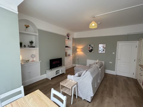 A cosy seating area with an L-shaped sofa, digital TV, and board games.