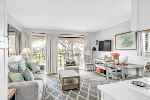 Bright living area with sliding glass doors opening to a balcony overlooking greenery.