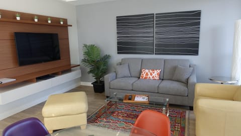 Welcome to your vibrant city retreat! Relax in this open-concept main living room showcasing sofa seating, accent chairs, and an integrated media console.