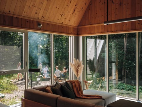 Gather with family, forest views framing outdoor fireside tales.