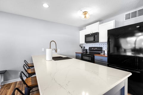 Modern kitchen with eat in bar and oven, dishwasher, microwave and refrigerator.