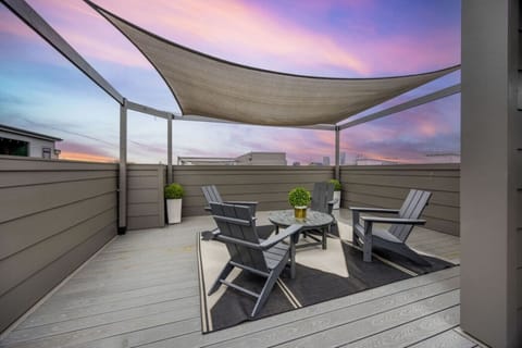 Unwind on the rooftop deck beneath a shade sail at sunset.