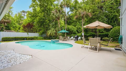 Multiple seating areas, shaded umbrellas, and a tranquil natural backdrop make this backyard oasis feel like your own private resort.