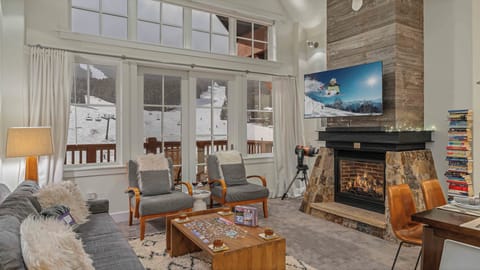 Living room with gas fireplace, TV, and front seat views to the slopes!