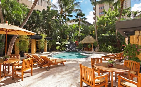 Unwind poolside under swaying palms with a refreshing swim, then relax on a lounge chair or gather at a tiki table surrounded by lush tropical greenery.