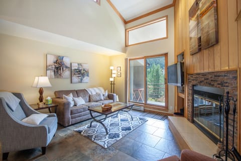 Open floor plan living room has a wood burning fireplace with mountain and ski run views