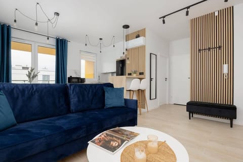 A bright living room with a dark blue sofa, coffee table, and access to a balcony. A great place to relax or spend time with friends and family.