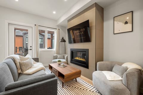 Living room with a gas-lit fireplace, 55` Smart TV, cozy seating options & walkout access to the hot tub.