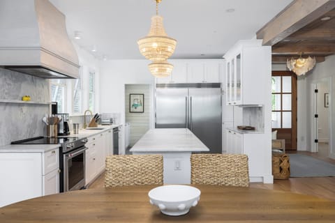 Spacious, modern kitchen featuring stainless steel appliances, quartz countertops, and designer lighting