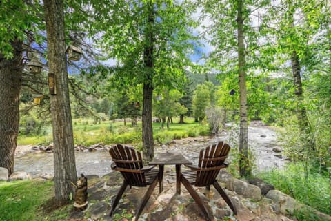 Elk River Cabin Adirondack chairs on riverbank in backyard.