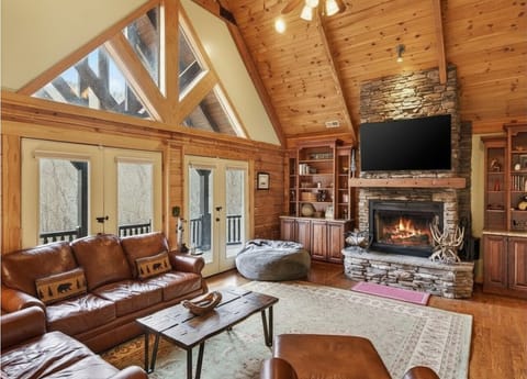 Impressive great room with TV for streaming, wood-burning fireplace, and access to the covered deck