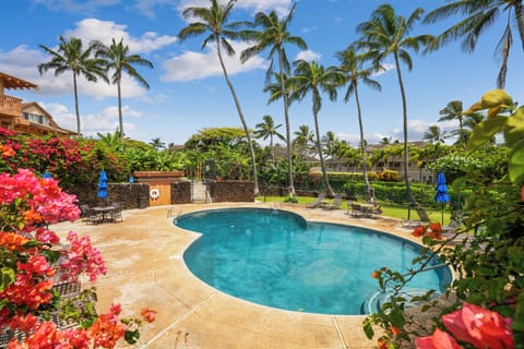A sparkling pool surrounded by swaying palms and vibrant tropical blooms invites your perfect island escape under sunny Hawaiian skies.