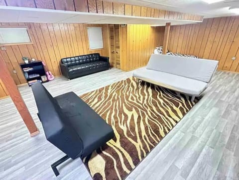 TV room with couches, futons, 75" smart TV, games, and desk area.