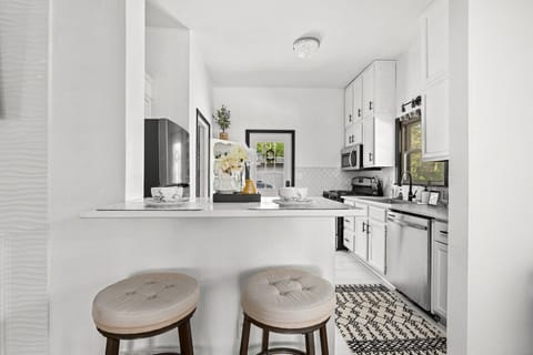 Modern kitchen with white cabinets, island, and stainless steel appliances.
