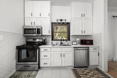 Well-equipped kitchen with white cabinetry and quartz countertops.