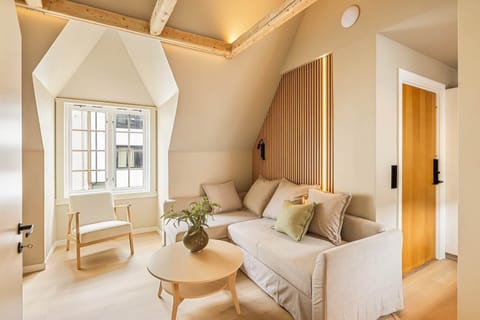 Inviting living room with plush sofa, natural light and charming attic-style ceiling
